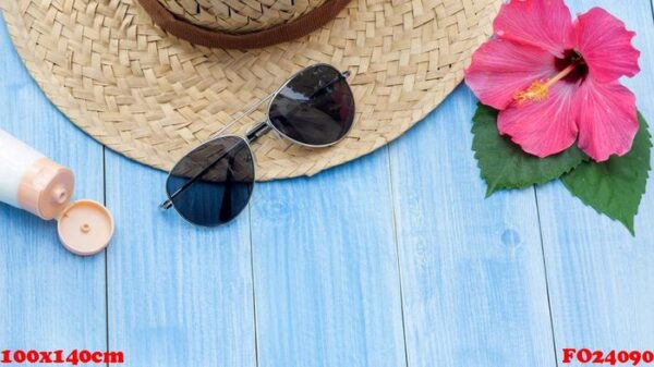 hat, sunglasses, sunblock and chinese rose flower on a blue wooden table.