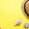 concept summer vacation. straw hat and shells on yellow background. copy space.