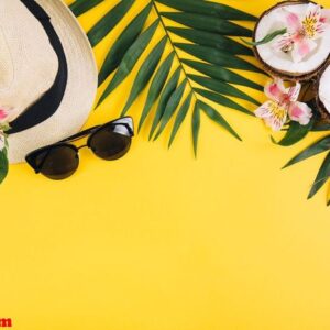 tropical palm leaves, hat, sunglasses, coconut on yellow backgro