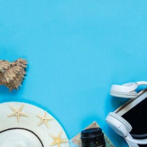 travel accessories camera, straw hat, card, shoes on a blue background flat top view layout with copy space