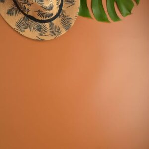 flat lay, top view workspace with eye glasses, notebook, hat, pencil, green leaf, shoes and coffee cup on brown background. summer stylish traveller blogger concept.