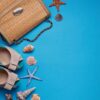 straw bag, shoes and seashells on blue background