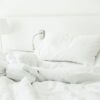 white pillow on rumpled bed