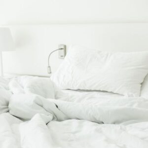 white pillow on rumpled bed