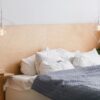 black and white bed with wooden bedhead in loft interior, geometric lights