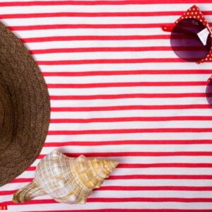 summer vacation, tourism, travel, holiday concept. sea shells, beach hat and striped blanket in white. top view with space for text.