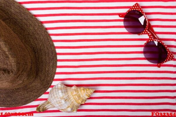 summer vacation, tourism, travel, holiday concept. sea shells, beach hat and striped blanket in white. top view with space for text.