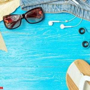 frame elegant female straw hat slippers jeans sunglasses on blue wooden background, copyspace for text, summer vacation.