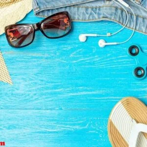 frame elegant female straw hat slippers jeans sunglasses on blue wooden background, copyspace for text, summer vacation.