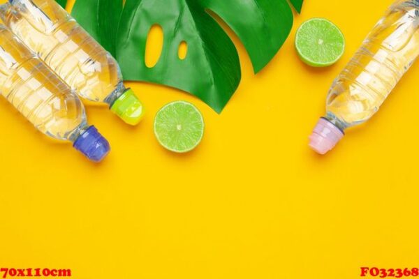 tropic leaves and bottle l water on yellow background. detox fruit infused water.