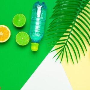 tropic leaves and bottle l water on yellow background. detox fruit infused water.