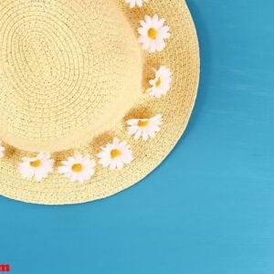 straw hat with camomile on a blue background. top view. summer background. flat lay.