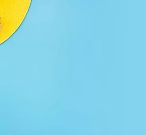 summer blue banner with yellow hat ,sunglasses and monstera leaf on blue background top view.