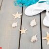 seashells and white flip flops grey wooden background. flat lay.