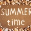 summer time is written on the sand in frame of sea shells. trave