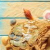 sea rope with many different sea shells on the sea sand on a blue wooden background. top view