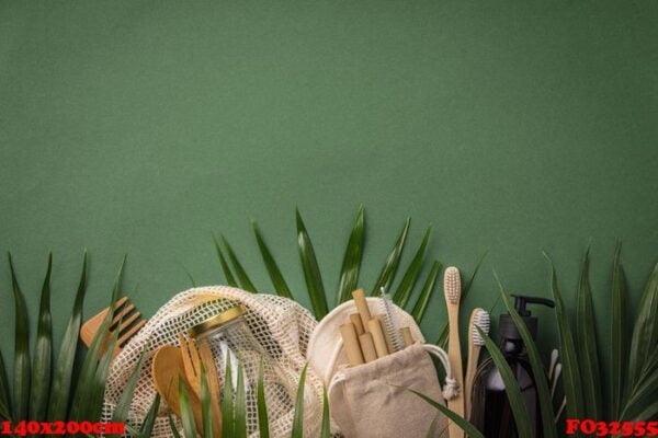 zero waste concept. cotton bag, bamboo cultery, glass jar, bamboo toothbrushes, hairbrush and straws on green background