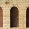 close up of three wooden doors and white brick wall