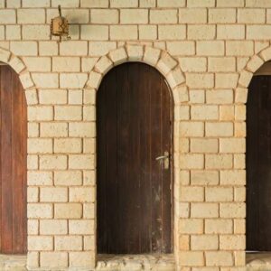 close up of three wooden doors and white brick wall