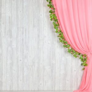 wooden gray wall with a pink curtain and flowers.