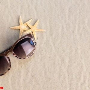 heap of shells and sunglasses lying on sand