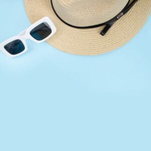 hat with sunglasses on a blue background, top view, summer conce