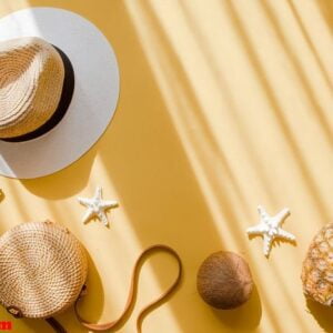 colorful summer female fashion outfit flat lay. straw hat, bamboo bag, sunglasses, coconut, pineapple, starfish over yellow background, top view. summer fashion, holiday concept