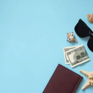 flat lay traveler accessories on blue background with sea shells, money, notepad and sunglasses. top view travel or vacation concept. summer background.