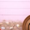 beach hat with seashells on pink wooden table