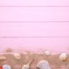 starfish and seashells with sand on a pink wooden background. summer concept