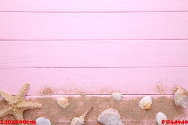 starfish and seashells with sand on a pink wooden background. summer concept