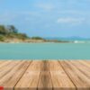 vintage wooden board empty table in front of blue sea & sky back