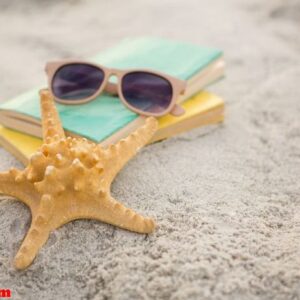 starfish, sunglasses and books on sand