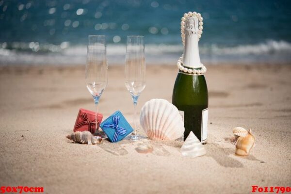 bottle of champagne on the beach with a gift boxes and shells