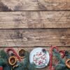 a cup of hot chocolate with marshmallows. christmas tree and decorations, cane caramel and oranges nuts wooden background copy space.