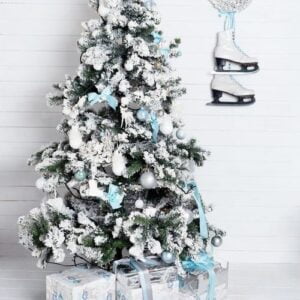 decorated christmas tree on white background with skates and wreath hanging on the wall. new year decoration, winter holidays.