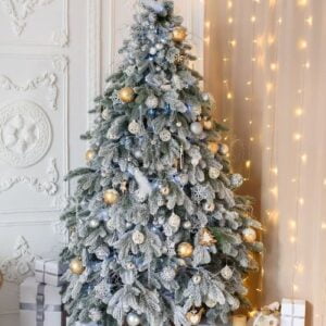 snow covered christmas tree with golden toys in the interior on a white stucco background