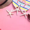 flat composition of summer beach accessories on pink background .