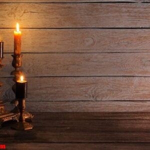 burning candles in candlesticks on old wooden background