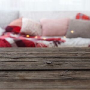 old wooden table on background sofa with pillows and plaids