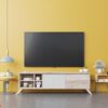 tv on cabinet in modern living room with lamp,table,flower and plant on yellow wall background.