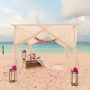 wedding arch on beach with tropical maldives resort and sea