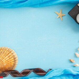 blank paper photo frame with starfish, shells and items on wooden table.