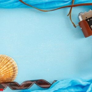 blank paper photo frame with starfish, shells and items on wooden table.