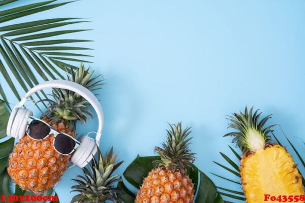 funny pineapple wearing white headphone, concept of listening music, isolated on colored background with tropical palm leaves, top view, flat lay design.