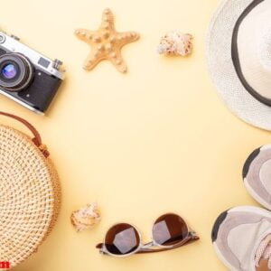 summer vacation background. sneakers, rattan bag, sunglasses, hat and retro camera on a yellow background. flat lay. copy space