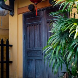 a beautiful black wooden door on a yellow wall with chinese lanterns. vietnam.