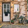 bicycle parked near a brick building decorated with plants at daylight