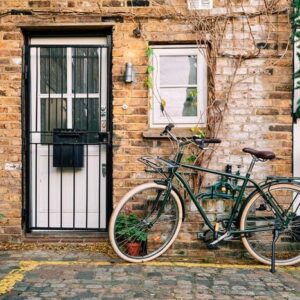 bicycle parked near a brick building decorated with plants at daylight