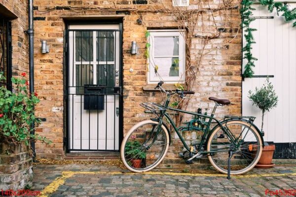 bicycle parked near a brick building decorated with plants at daylight